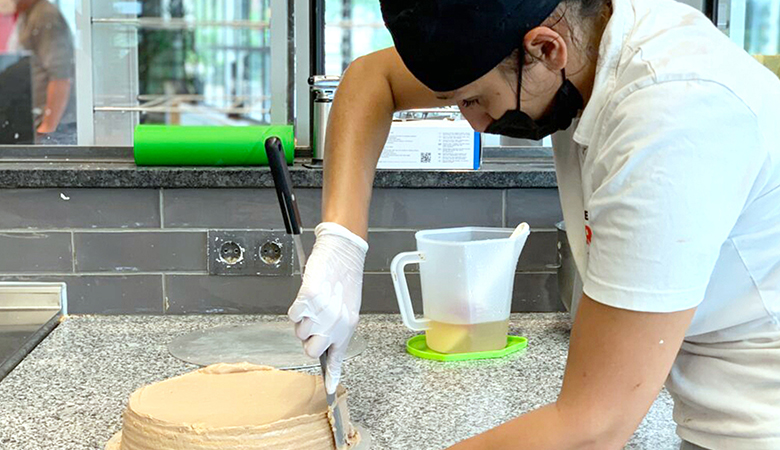 Eine Auszubildende fertigt einen Kuchen an.