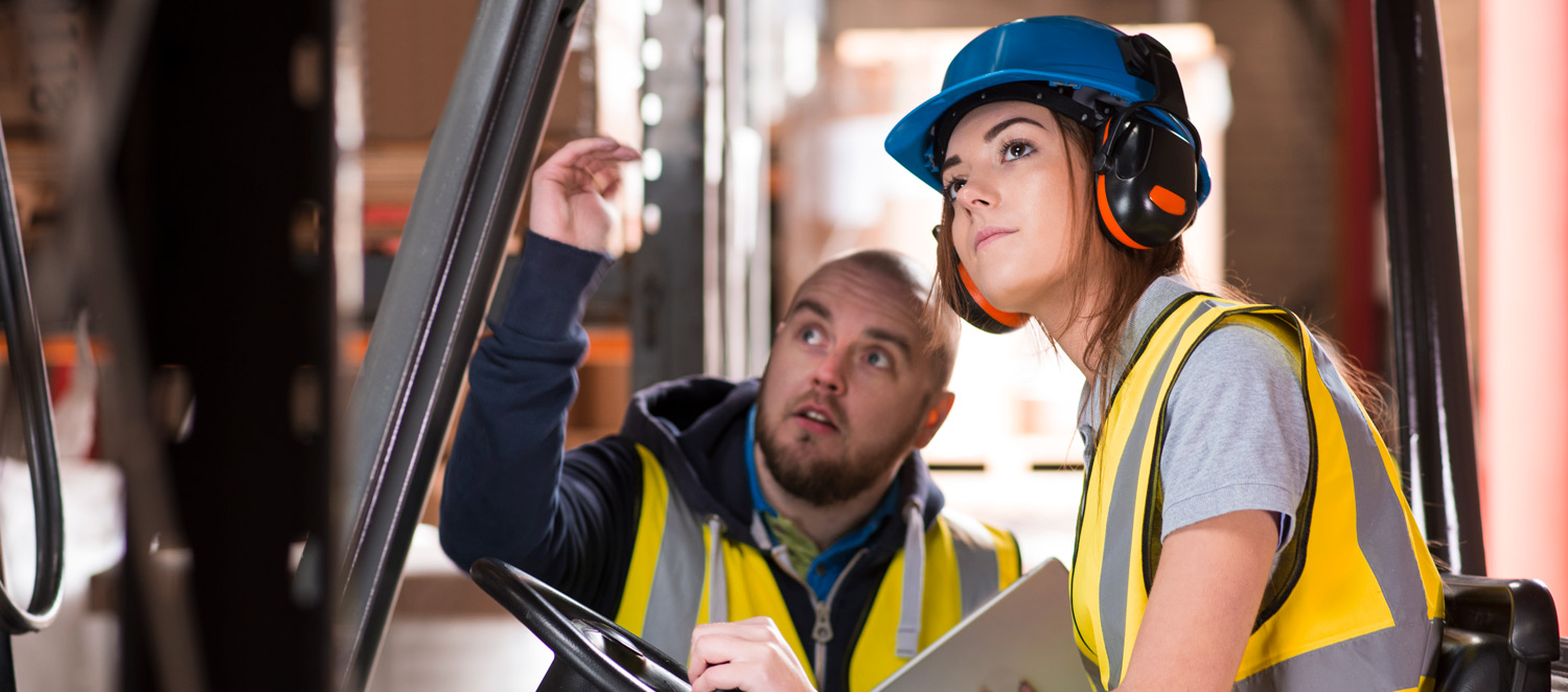 Eine Frau und ein Mann in Arbeitskleidung inspizieren eine Metallkonstruktion.